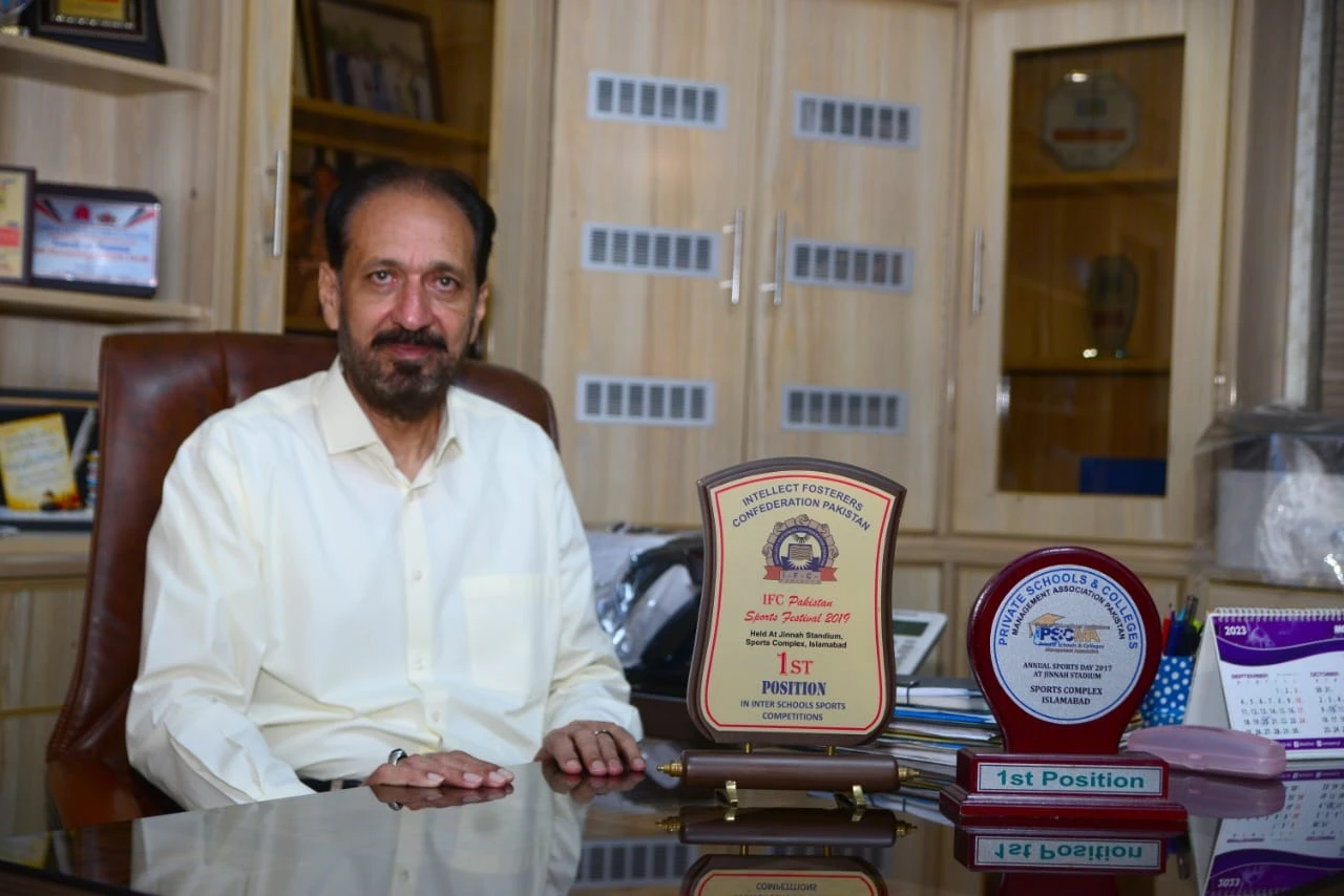 Ch. Muhammad Tayyab, Director, at his desk with the school's first-position sports trophies